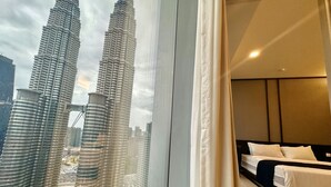 Una habitación de hotel con una cama y un ventanal que ofrece vistas a las Torres Petronas.