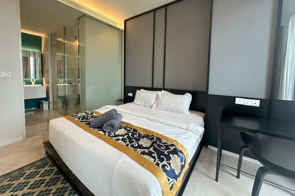 Una habitación de hotel moderna con una cama grande, un escritorio y una zona de ducha de vidrio.