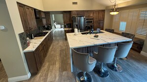 Una cocina moderna con una isla grande, armarios de madera oscura y encimera de mármol.