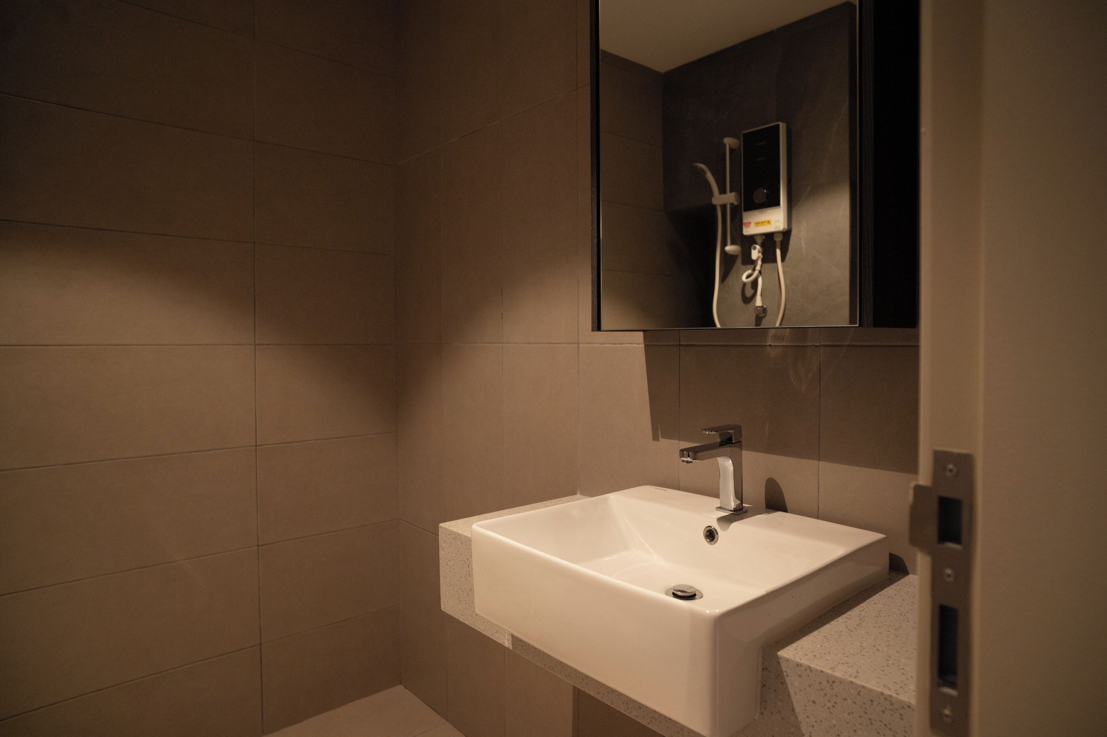 A bathroom with a white sink, a mirror, and a shower with a handheld showerhead.