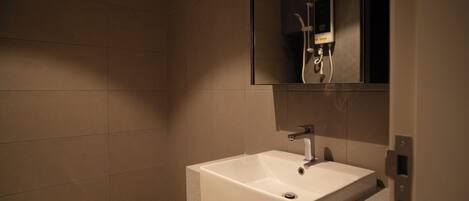 A bathroom with a white sink, a mirror, and a shower with a handheld showerhead.