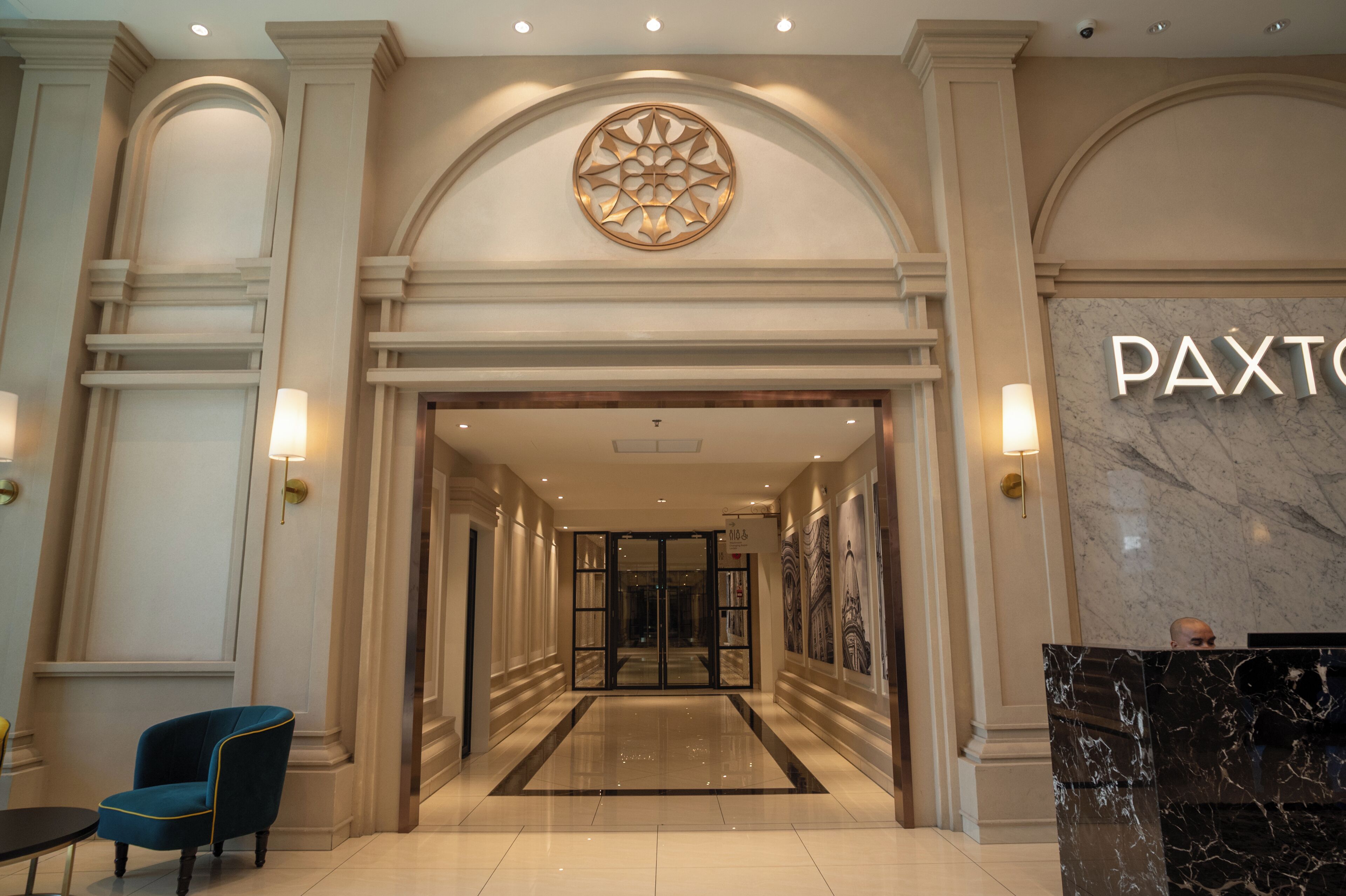 A hotel lobby with a marble reception desk, a blue chair, and a geometric wall design.