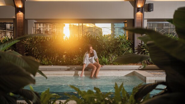 A woman sitting in a pool with a modern building in the background. - Paxtonz Mana-Mana Suites Kuala Lumpur (Petaling Jaya)