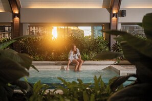 A woman sitting in a pool with a modern building in the background. - Paxtonz Ango Suites Kuala Lumpur (Petaling Jaya)
