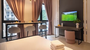 A modern hotel room with a bed, two chairs, a desk with a TV, and a window with curtains. - Paxtonz Mana-Mana Suites Kuala Lumpur (Petaling Jaya)