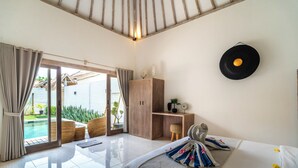 Un dormitorio moderno con una cama grande, un armario de madera, un escritorio y vistas a una piscina.