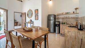 Una cocina moderna con zona de comedor, que incluye una mesa de madera, sillas de mimbre y una isla integrada con estufa.