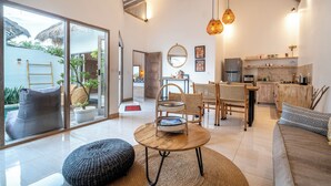Una sala de estar moderna con un gran ventanal que da a un balcón, una mesa redonda de madera y un rincón de estar acogedor con un sofá y sillones.