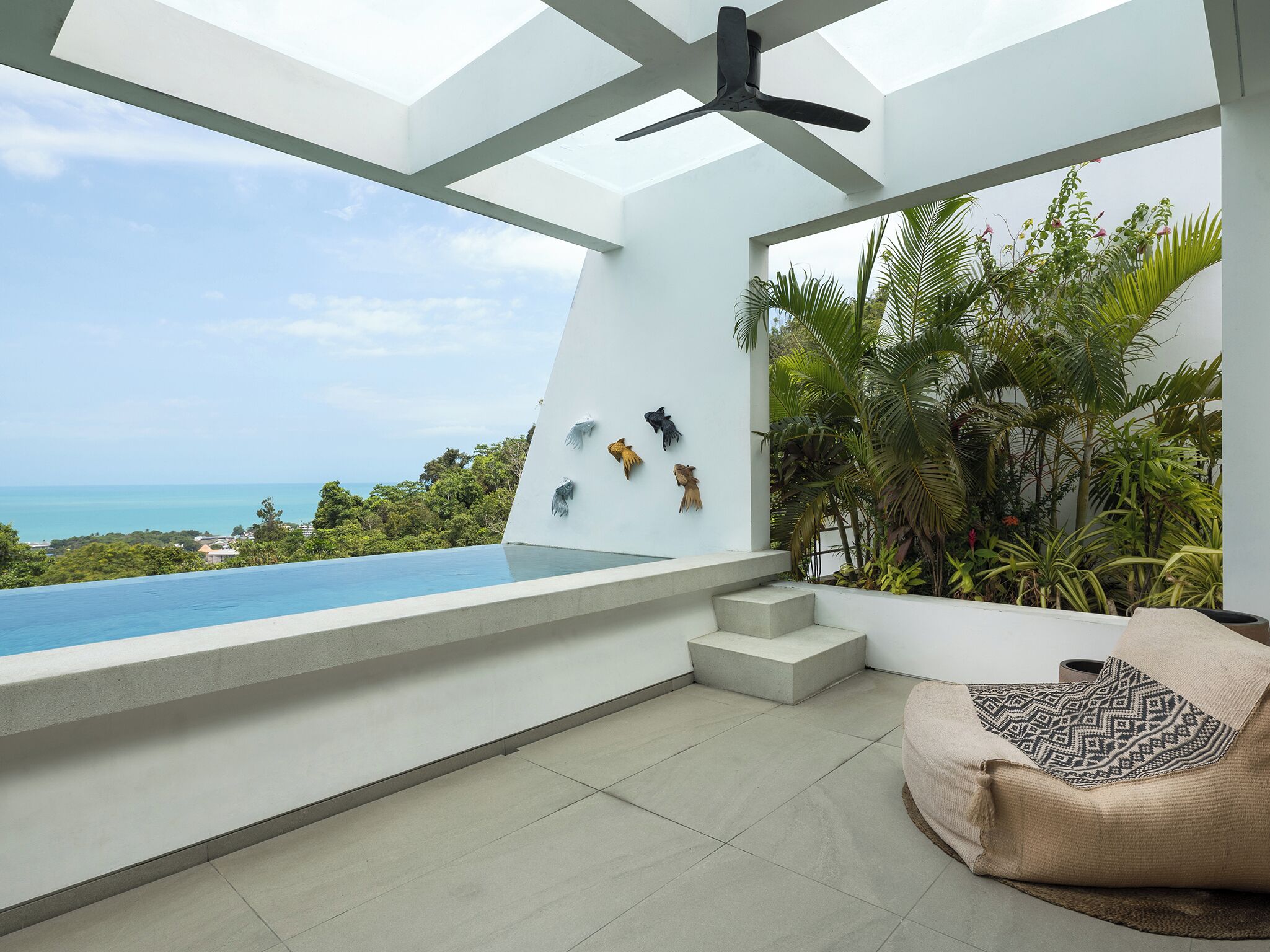 A modern room with a large window overlooking a pool and ocean.