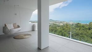 Ein modernes Zimmer mit Hängekorbschaukel, runder Teppich und großem Fenster mit Blick auf die Stadt.