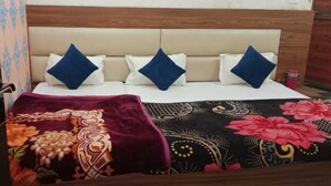 A bed with a floral bedspread, a headboard, and multiple pillows. - The Mansarovar Palace (Faizabad)