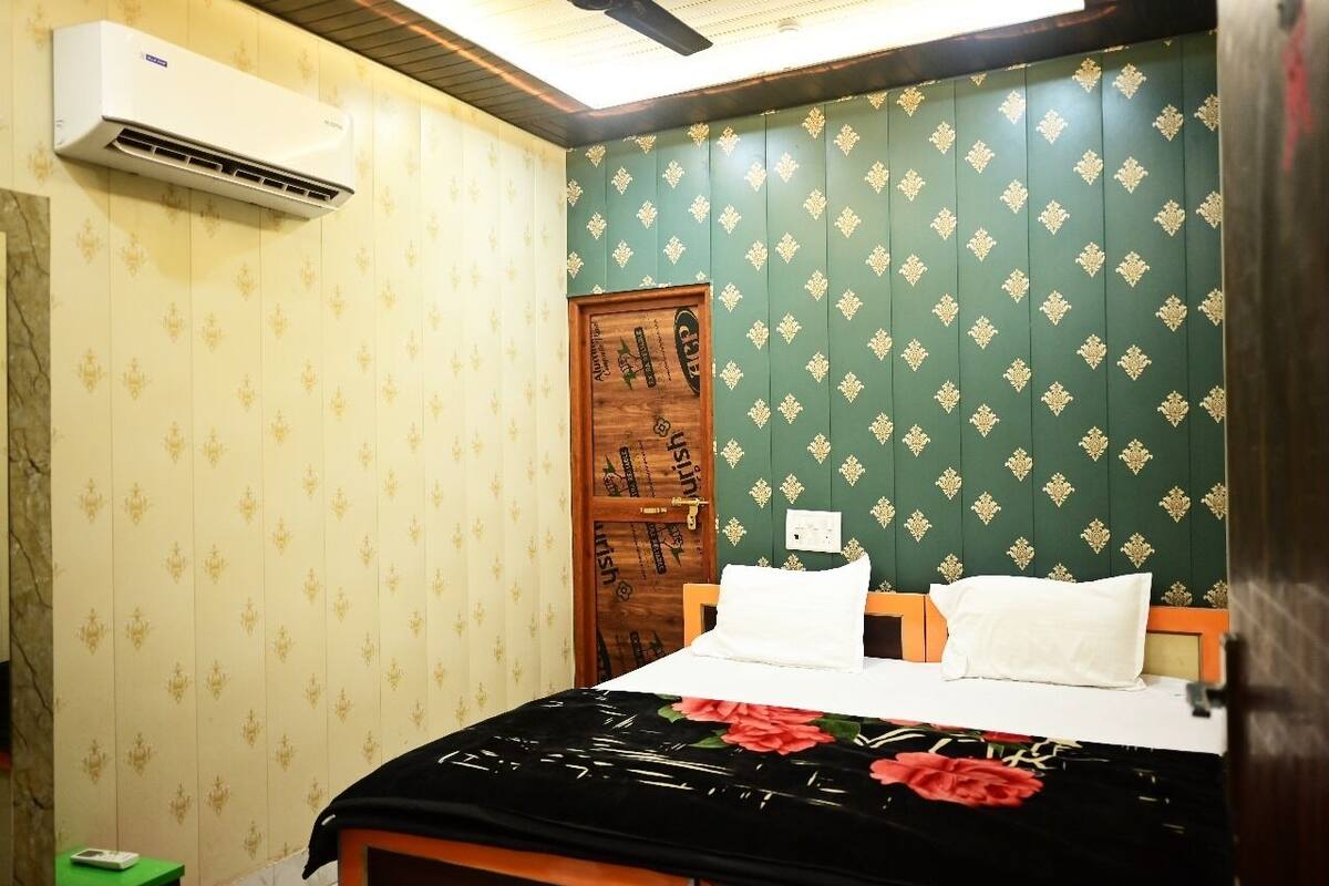 A room with a bed, a wooden door, and an air conditioning unit.