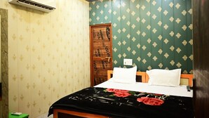 A room with a bed, a wooden door, and an air conditioning unit. - The Mansarovar Palace (Faizabad)