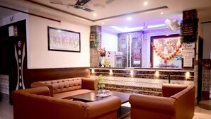 A reception area with a brown sofa, a small table, and a decorative wall with a framed picture and a cash counter. - The Mansarovar Palace (Faizabad)