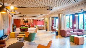 Un hall d'entrée moderne avec des lambris en bois au plafond, une table de billard, des sièges confortables et de grandes fenêtres.