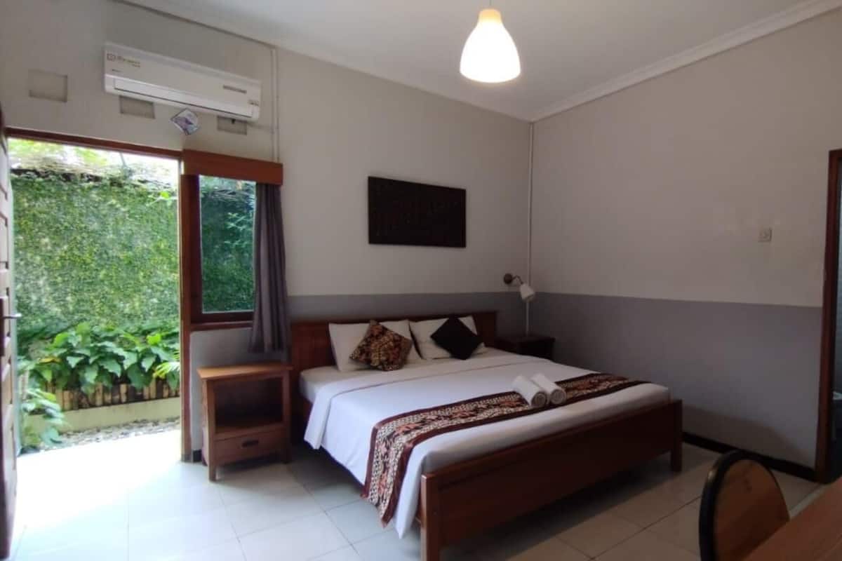 Une chambre à coucher avec un lit, une table de chevet et une fenêtre.