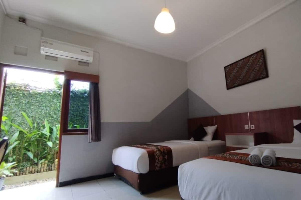 Une chambre d’hôtel avec deux lits, une fenêtre, un appareil de climatisation et un luminaire au plafond.