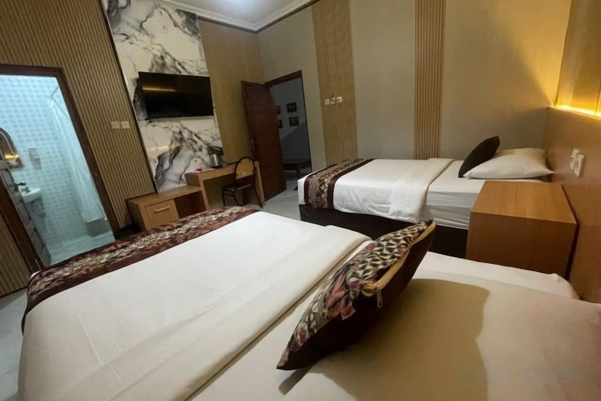 Habitación de hotel con dos camas, un escritorio, una silla, un televisor y un baño.