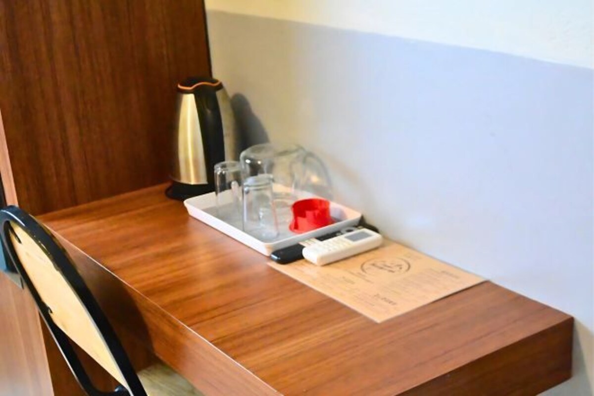 Une table en bois sur laquelle se trouve un plateau contenant une tasse rouge, un appareil blanc et un verre.