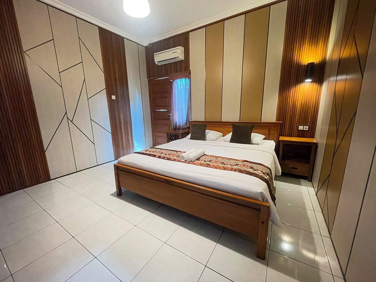 Une chambre moderne avec un grand lit, une table de chevet, une armoire et un appareil de climatisation.