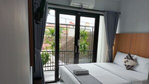 Una camera d'albergo con un letto, un balcone e una vista, più una porta con un cartello.