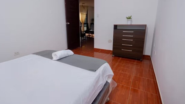 Une chambre à coucher avec un lit, une commode et une petite plante.