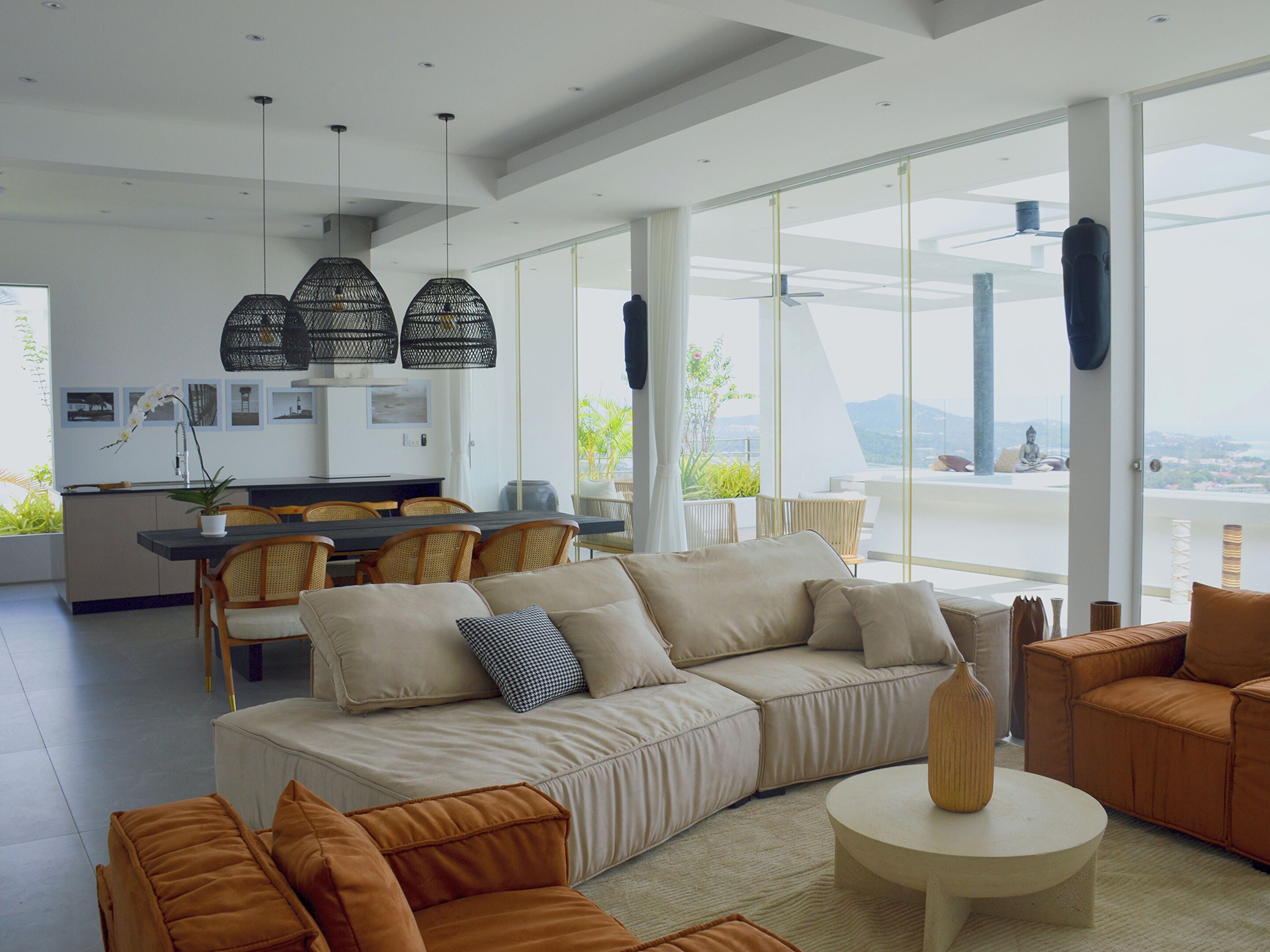 A modern living room with a large sofa, a coffee table, and a dining area with chairs and a table.