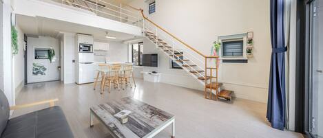 Un apartamento moderno con cocina, comedor y una escalera que lleva a un nivel superior.