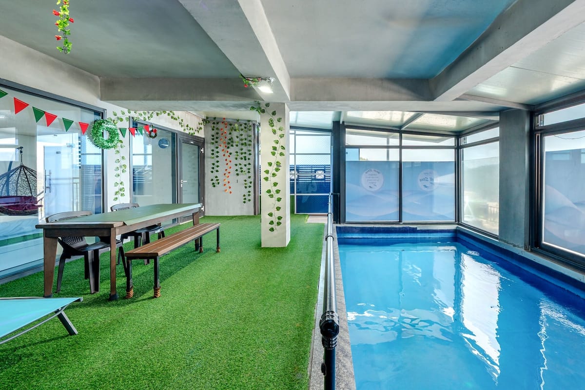 Un área de piscina interior con césped artificial, una mesa de billar y un espacio de descanso.