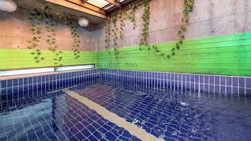 A swimming pool with tiled walls and a tiled floor, surrounded by a green and blue color scheme.