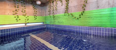 A swimming pool with tiled walls and a tiled floor, surrounded by a green and blue color scheme.