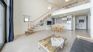 Un amplio espacio de sala con una escalera, una mesa de comedor y una cocina al fondo.