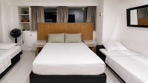 A hotel room with a central bed, two single beds on either side, a wooden headboard, a bedside table, a fan, and a shelf with items. - Ocean view with balcony—pool—Bocagrande Beach—Pet-friendly (Cartagena de Indias)