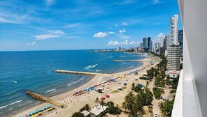 Un paysage urbain côtier avec une plage, des immeubles de grande hauteur et un ciel dégagé.