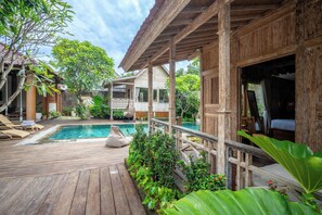 A wooden deck with a pool, lounge chairs, and a covered seating area. - Meraki Luxury Villa (Pemuteran)