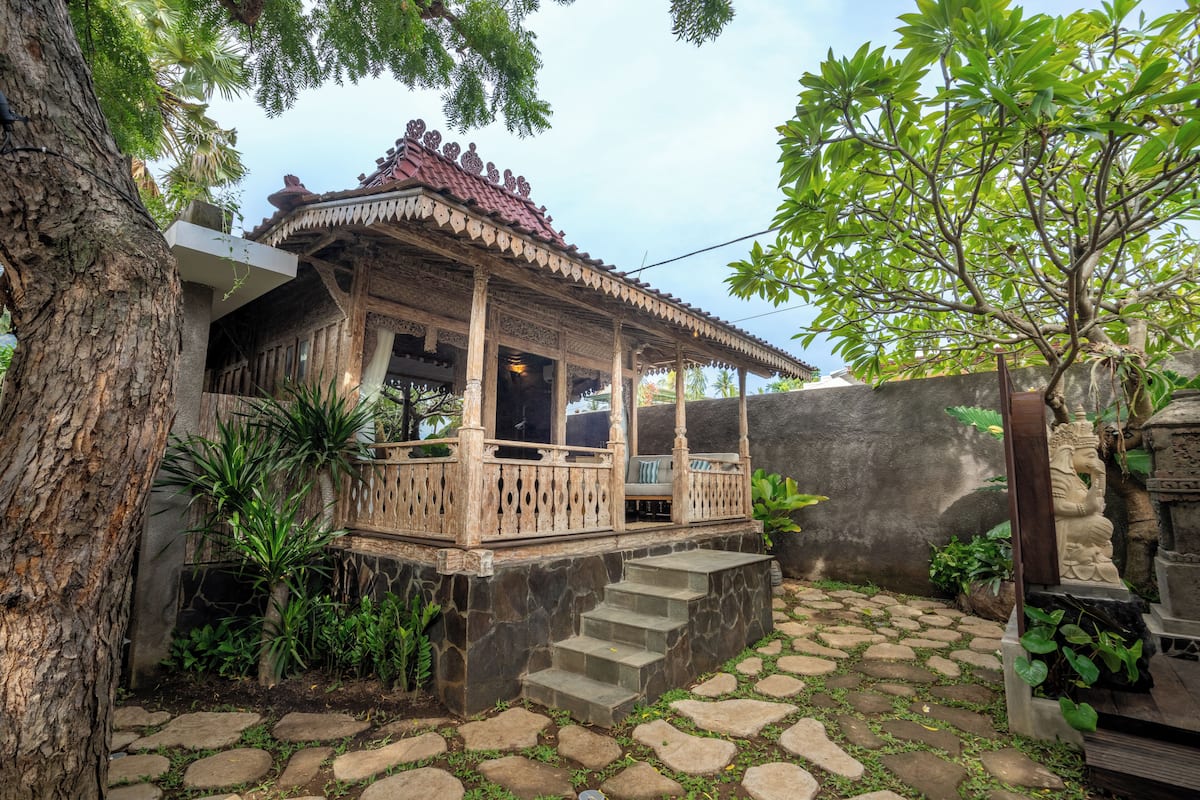 A traditional wooden structure with a tiled roof, stone steps, and a stone wall.