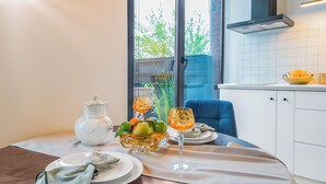Une table à manger dressée avec des assiettes, des verres et un saladier de fruits.