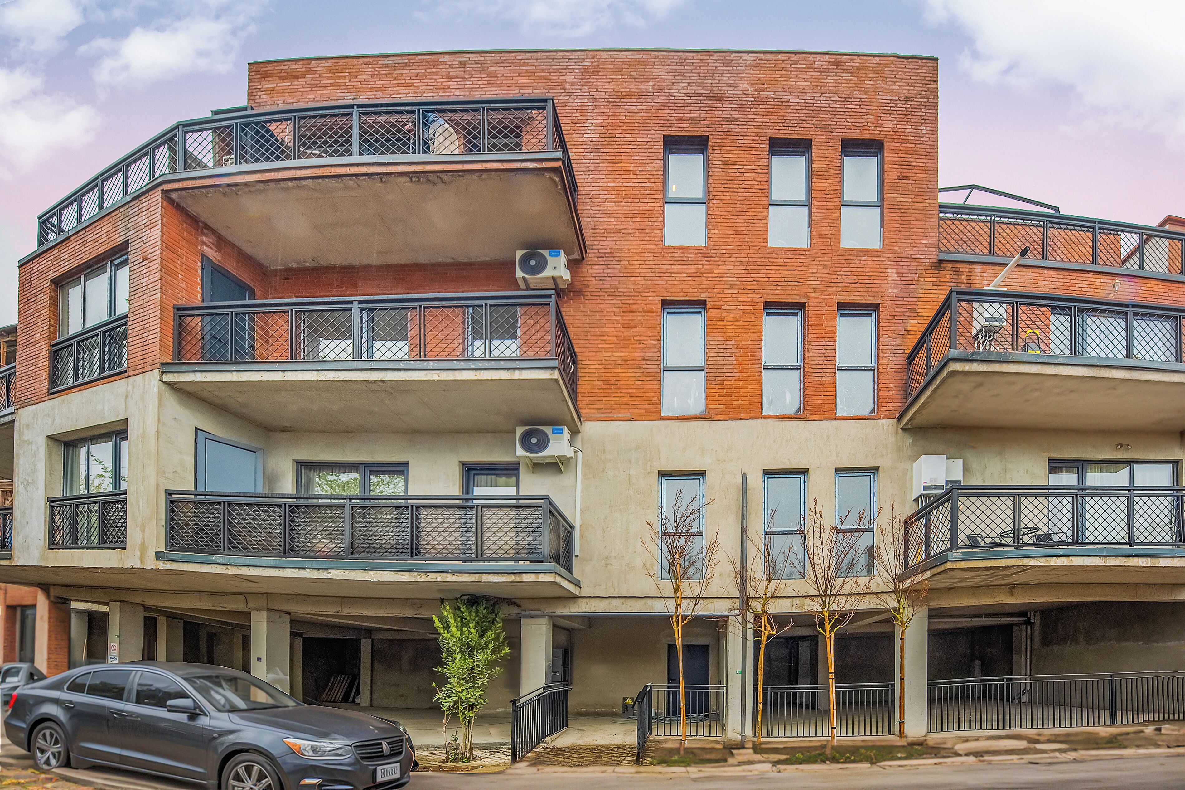 Un edificio residencial de varios pisos con balcones, unidades de aire acondicionado y un garaje.