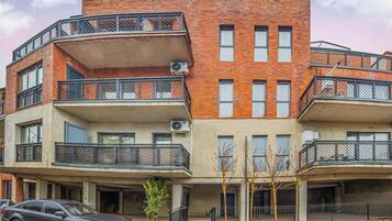 Un edificio residencial de varios pisos con balcones, unidades de aire acondicionado y un garaje.