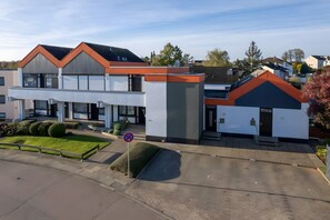Ein modernes Gebäude mit flachem Dach, einem Parkplatz und einem Verbotsschild.