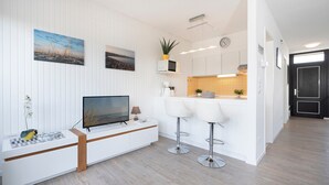 Una cocina moderna con armarios blancos, microondas integrado y una pequeña isla con taburetes de bar.