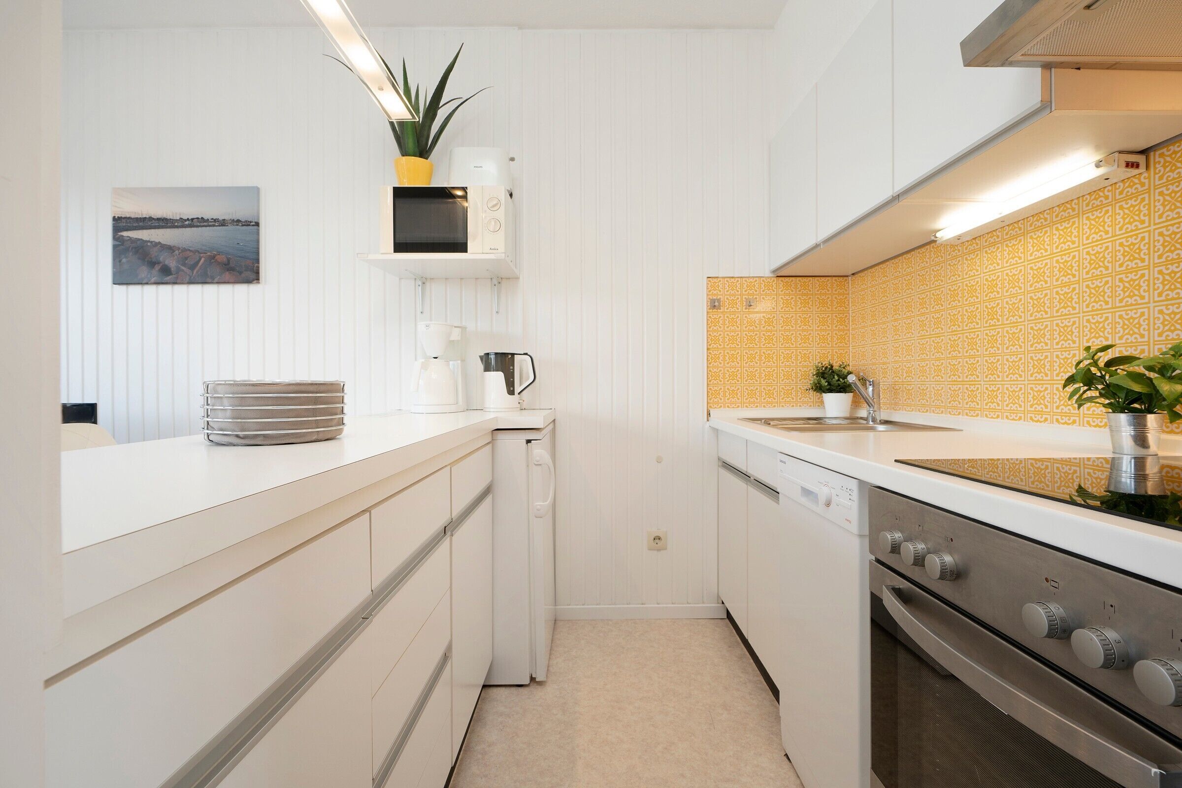 Une cuisine moderne avec des meubles blancs, un four en acier inoxydable, un micro-ondes et un évier.