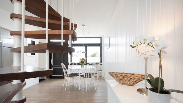 Un interior moderno con comedor, escalera y planta en maceta.