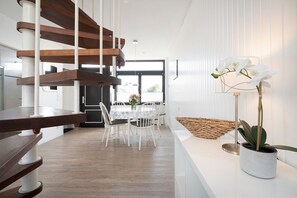 Ein modernes Interieur mit Essbereich, einer Treppe und einem Blumentopf.