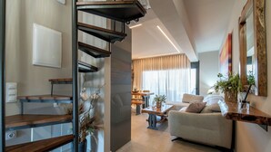 A modern living room with a sofa, coffee table, and a staircase with wooden shelves. - Seaside Suite 3-Modern & Comfort (Episkopos)