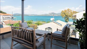 A balcony with wooden furniture, a view of the sea, and a satellite dish. - Seaside Suite 3-Modern & Comfort (Episkopos)