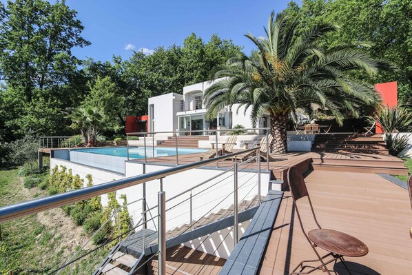 Une villa moderne dotée d’une piscine, d’un espace salon extérieur et d’une végétation luxuriante.