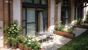 A building with large windows, outdoor seating, and potted plants. - Tenuta Molino dei Sassi (Zevio)