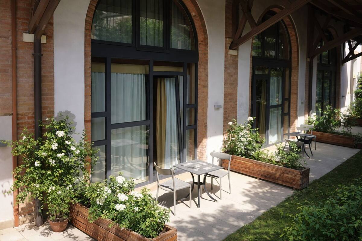 Un edifici amb finestrals amplis, terrassa a l'exterior i plantes en testos.