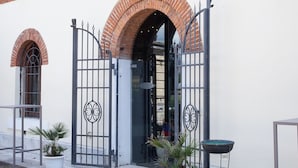 A building with a white facade, red brick arches, and a black metal gate. - Tenuta Molino dei Sassi (Zevio)